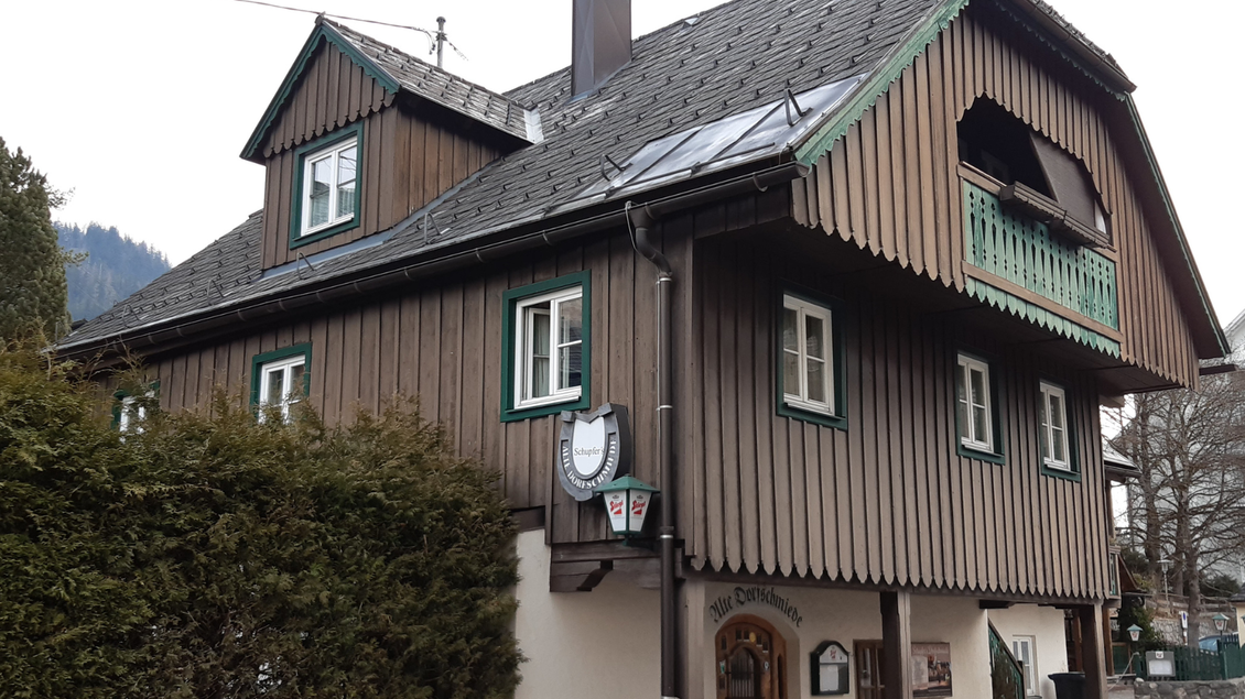 Ein traditionelles Holzhaus mit einem grünen Balkon. Der Himmel ist bewölkt und die Umgebung ist ländlich. | © TVB Ausseerland Salzkammergut_Daniela Casari