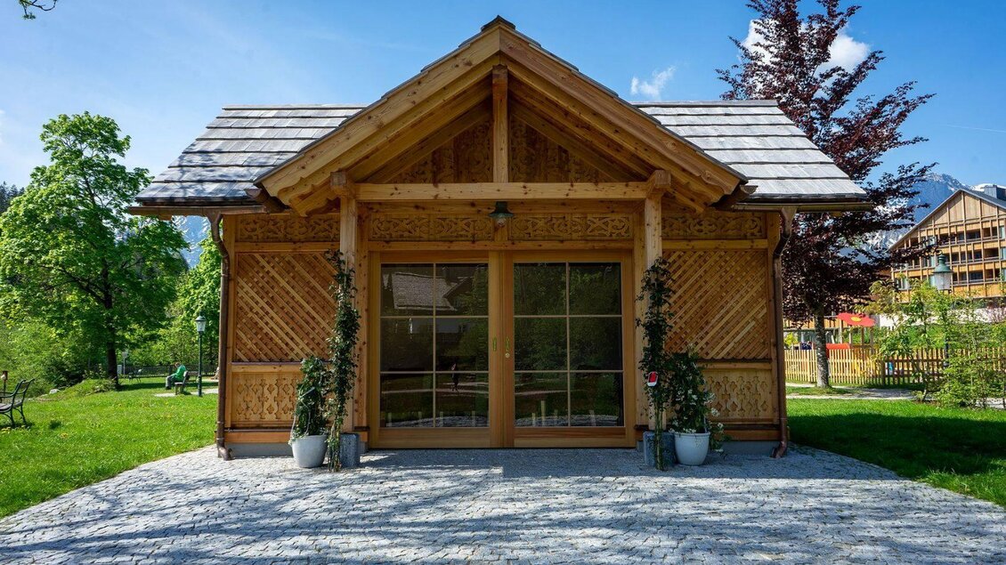 <p>Ein rustikales Holzhaus mit einem schönen Dach und großen Fenstern. Umgeben von grünem Gras und Bäumen unter blauem Himmel.</p> | © Lebensbilder_Christine-Struz