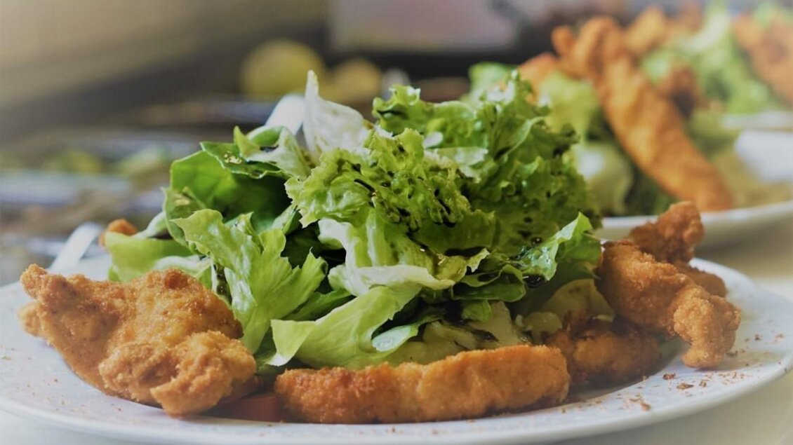 Ein Teller mit knusprigen Hähnchenstücken und frischem Salat. Die Zutaten sind appetitlich angerichtet und verleihen dem Gericht Farbe. | © Seerestaurant Gruber