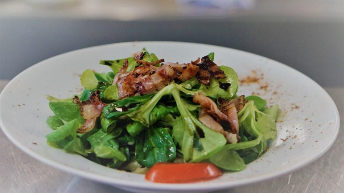 Ein frisch zubereiteter Salat auf einem weißen Teller. Der Salat enthält grünes Blattgemüse und einige Stücke von gebratenem Fleisch. | © Seerestaurant Gruber