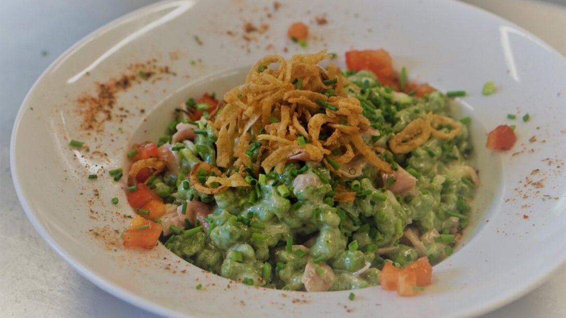 Ein bunter Salat mit grünen Zutaten, gewürfelten Tomaten und knusprigen Zwiebelringen obendrauf. Das Gericht ist frisch und ansprechend serviert. | © Seerestaurant Gruber