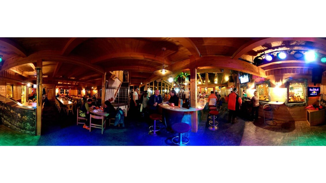 Eine gemütliche Bar mit Holzinterieur und warmem Licht. Gäste genießen die Atmosphäre und Unterhaltung in einem lebhaften Ambiente. | © Jürgen Manfred Pröll