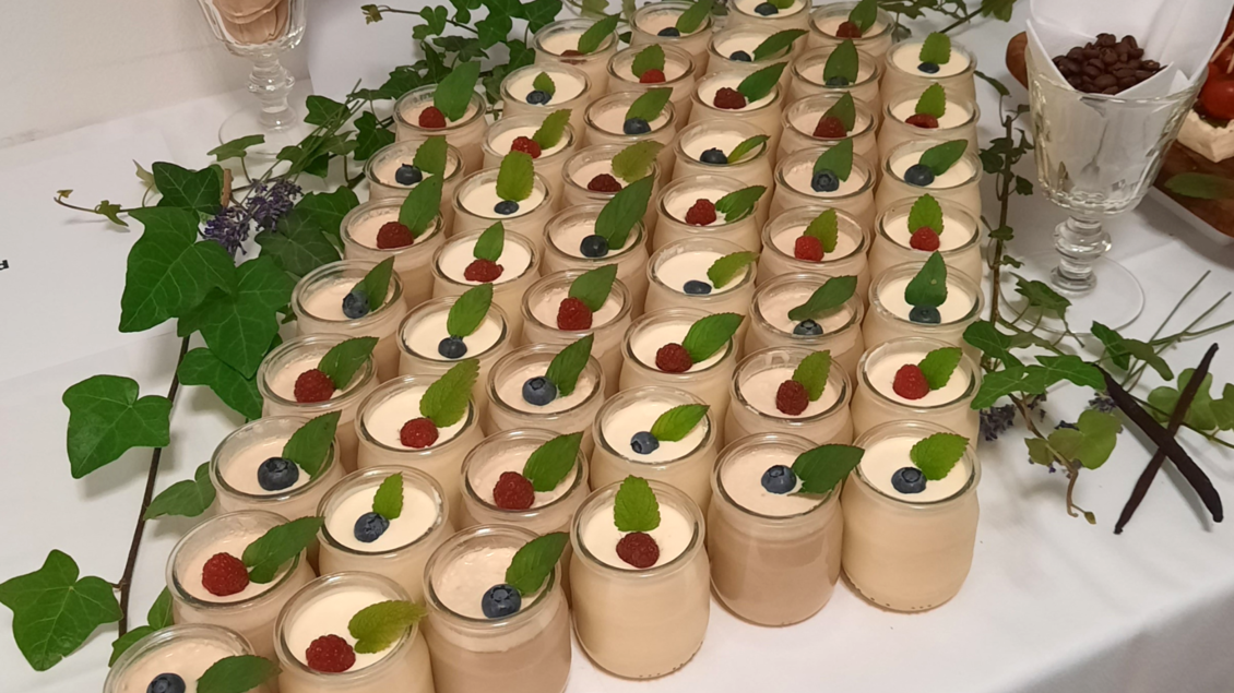 Eine Vielzahl von Dessertgläsern steht auf einem Tisch. Jedes Glas ist mit einer Schicht Creme, Beeren und einem Blatt Minze dekoriert. | © Butterer Hofladen