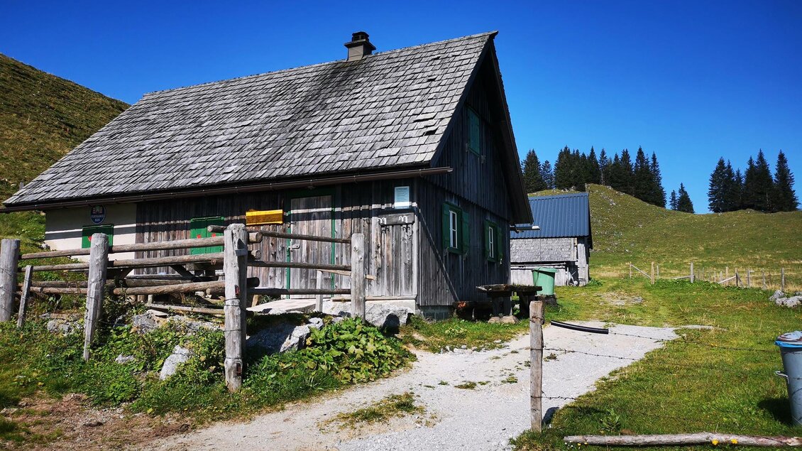 Ein traditionelles Holzhaus in einer ländlichen Umgebung. Im Hintergrund sind grüne Hügel und Nadelbäume zu sehen. | © TV Hochsteiermark / Brigitte Digruber