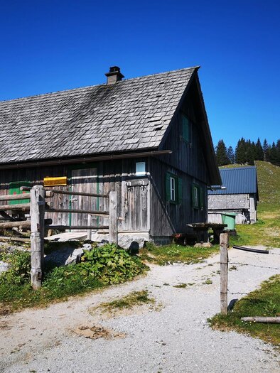 A traditional wooden house in a rural setting. In the background, green hills and coniferous trees can be seen. | © TV Hochsteiermark / Brigitte Digruber