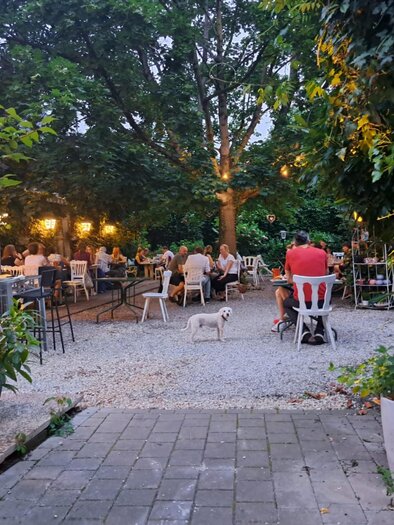 Gäste im abendlich beleuchteten Gastgarten des Restaurants Simply Greek Graz mit Bäumen und Lichtern. | © Galghoura