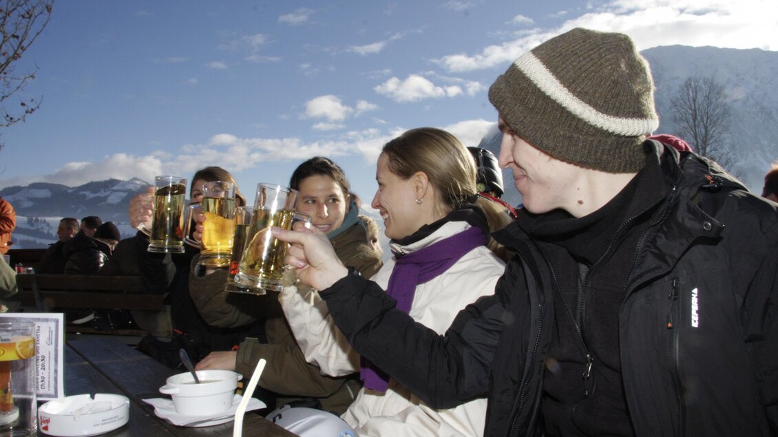<p>Zahlreiche Gäste genießen bei traumhaften Wetter Essen und Getränke bei der Skihütte Grafenwiese in Tauplitz. Im Hintergrund sind Berge und ein klarer Himmel zu sehen.</p> | © Grafenwiese Tauplitz