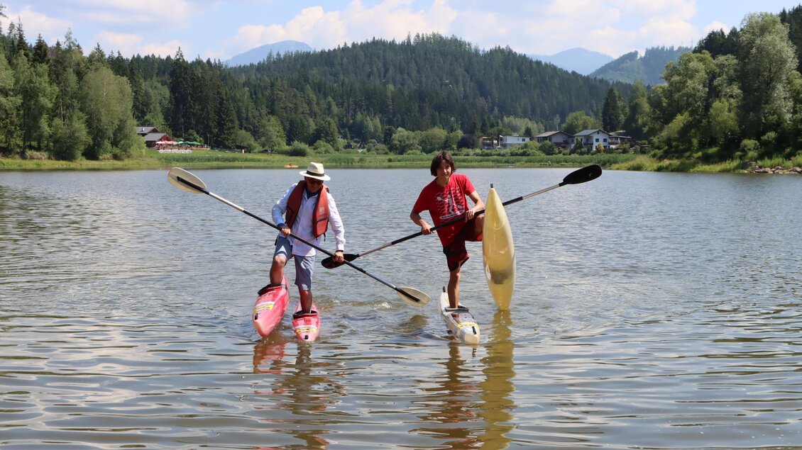 Zwei Männer paddeln auf einem ruhigen See. Im Hintergrund sind Wälder und Berge zu sehen. | © TVB Erzberg-Leoben