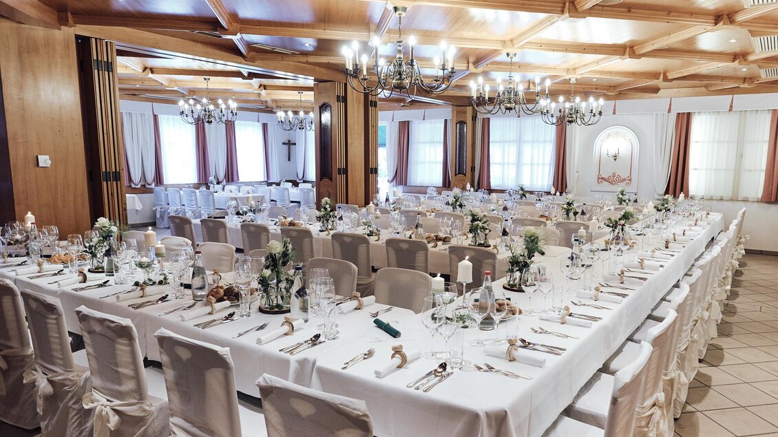 Ein eleganter Festsaal mit einem langen Tisch, der geschmackvoll gedeckt ist. Die Dekoration umfasst Blumen und Kerzen, und der Raum hat eine warme, einladende Atmosphäre. | © Sorgerhof