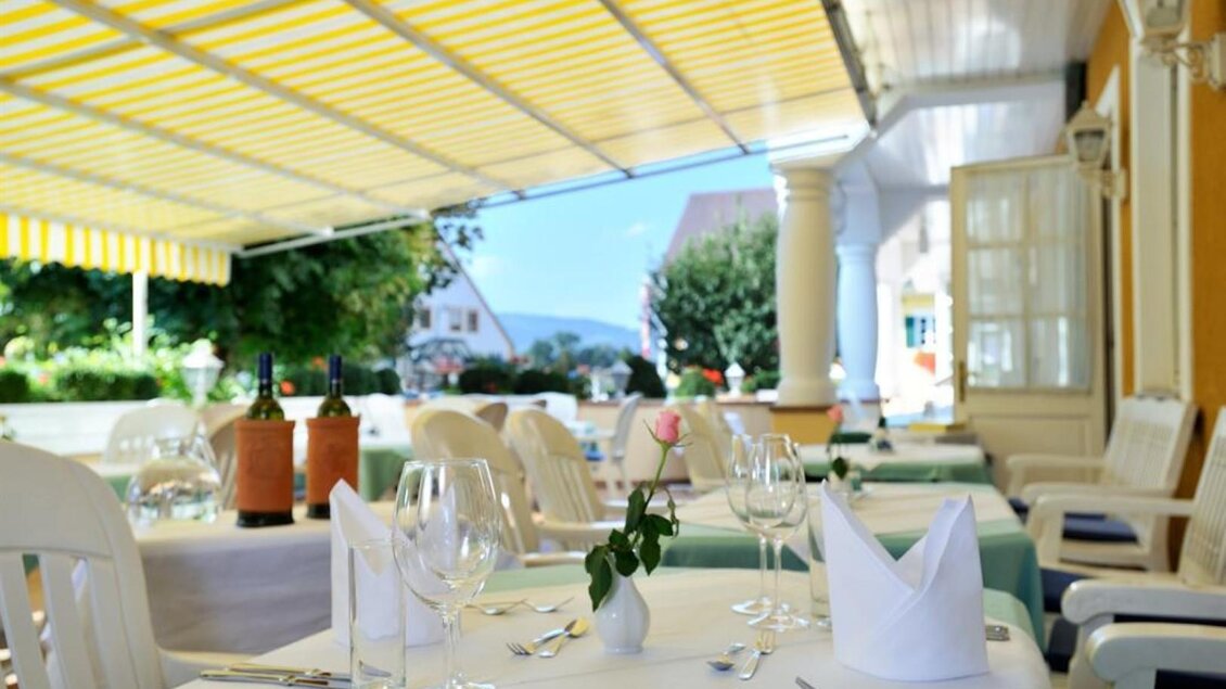 Ein schönes Restaurant mit Außenterrasse, gedeckt mit weißen Tischdecken und eleganten Gläsern. Im Hintergrund sieht man eine grüne Landschaft und einen blauen Himmel. | © Sorgerhof