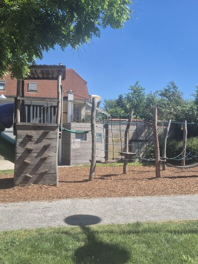 Ein Spielplatz mit einer Rutsche, Schaukeln und Klettergerüst. Die Umgebung ist grün und einladend. | © Petra Stossier