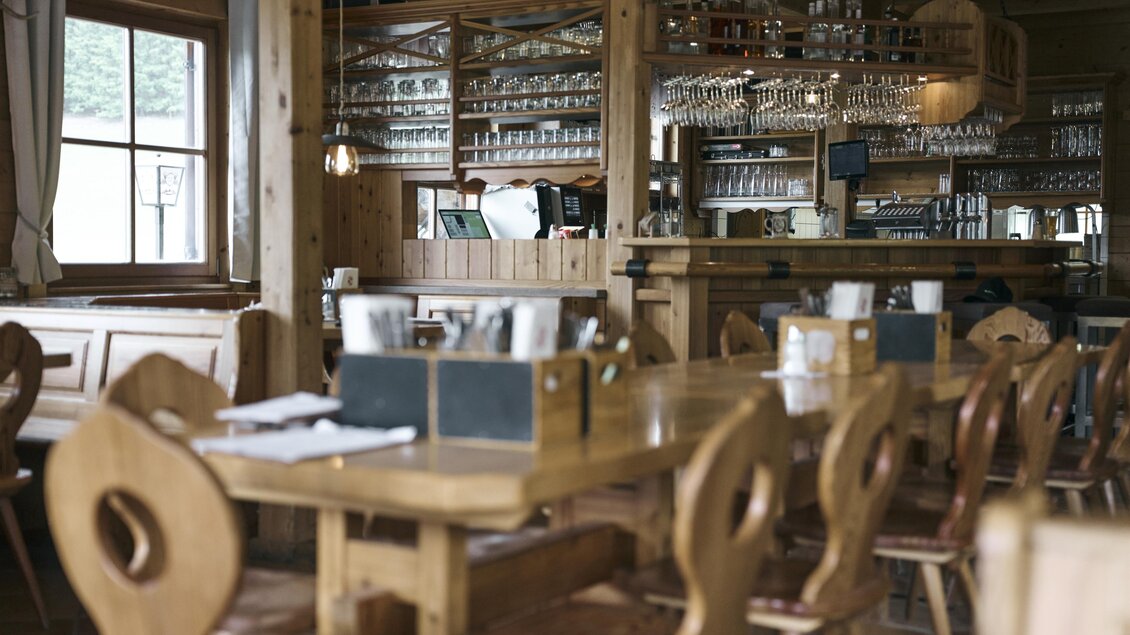 Ein gemütliches Restaurant mit Holzmöbeln und einer warmen Atmosphäre. Die Bar ist gut bestückt und im Hintergrund stehen Gläser ordentlich gereiht. | © Nationalpark Gesäuse