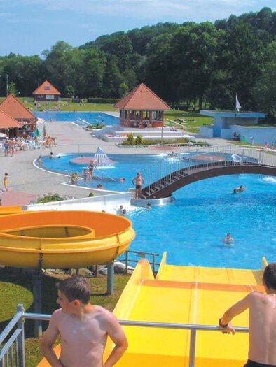 A swimming pool with various pools and a large slide. Many people are there to relax and swim. | © Städtisches Bad Leibnitz