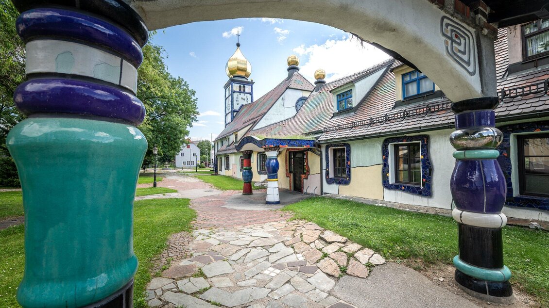 Farbenfrohe Säulen rahmen den Blick auf die von Hundertwasser gestaltete St. Barbara Kirche in Bärnbach | © TV Region Graz - Die Abbilderei