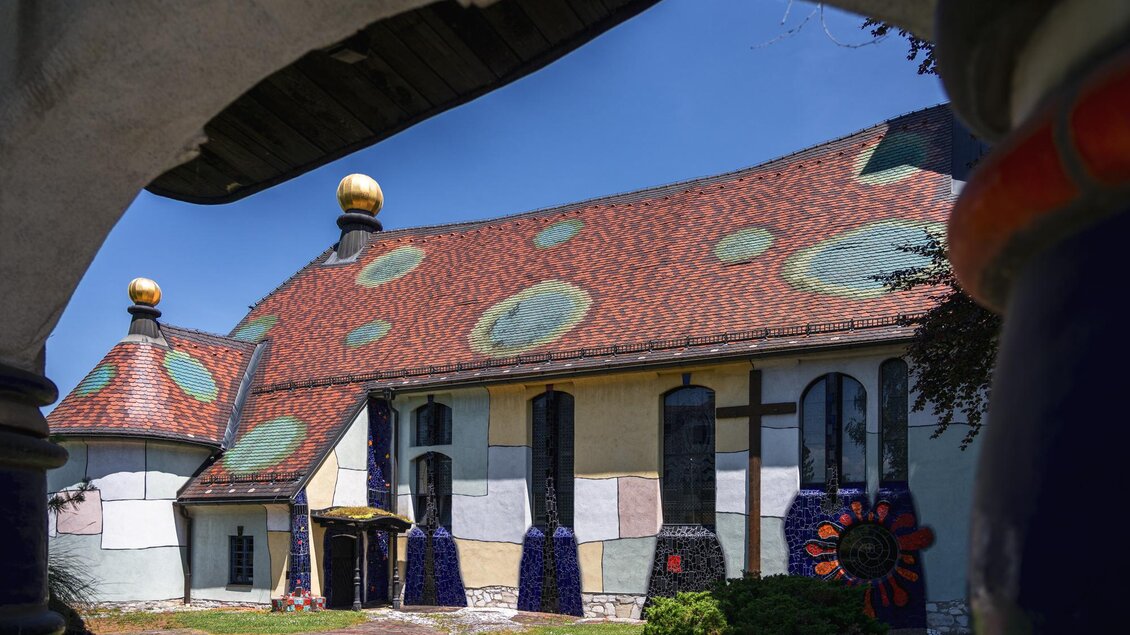 St. Barbara Kirche in Bärnbach mit von Hundertwasser gestaltetem Ziegeldach, Säulen und farbigen Fassadendetails | © Region Graz_Bernd Grosseck