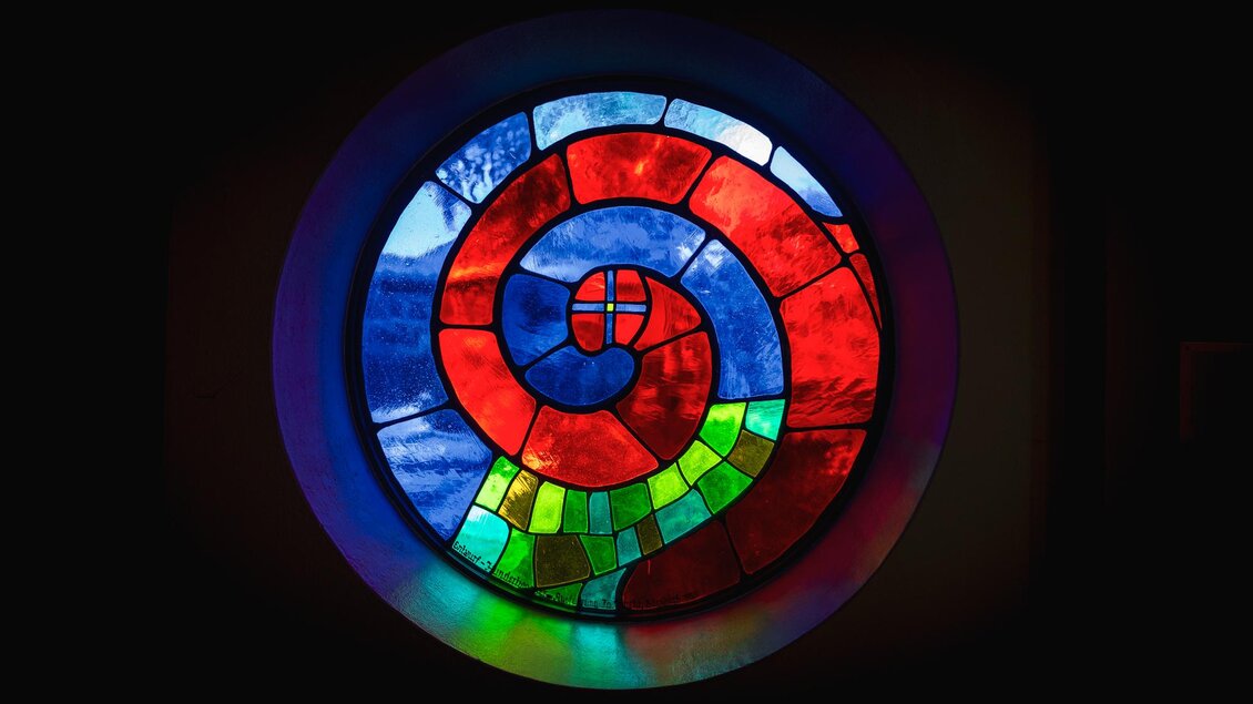 Rundes Buntglasfenster der St. Barbara Kirche in Bärnbach mit spiralförmigem Muster in Rot, Blau und Grün | © Region Graz_Bernd Grosseck