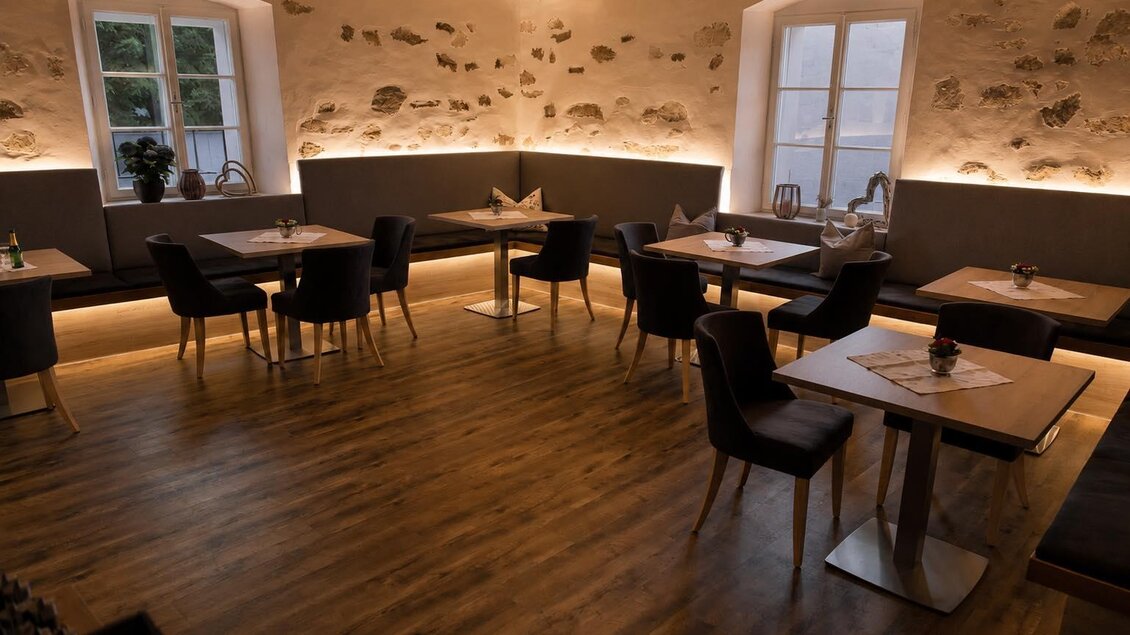 Ein modernes Restaurant mit Holzfußboden und stilvoller Beleuchtung. Die Tische sind ordentlich gedeckt und bieten Platz für Gäste. | © Stadtheuriger/Fred