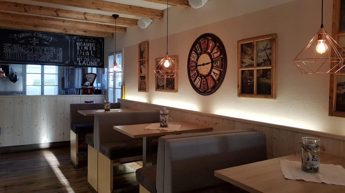 Eine gemütliche Restaurantumgebung mit modernen Holzmöbeln und warmem Licht. An den Wänden hängen schöne Bilder und eine große Uhr. | © Stadtheuriger Mariazell