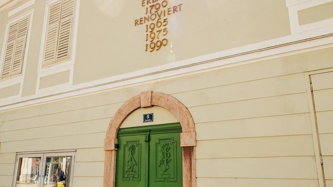 Ein Stadtteather mit einer auffällig grünen Tür und einer hellen Fassade. Die Gebäudeinschrift zeigt die Jahreszahlen der Renovierungen. | © TVB Erzberg-Leoben