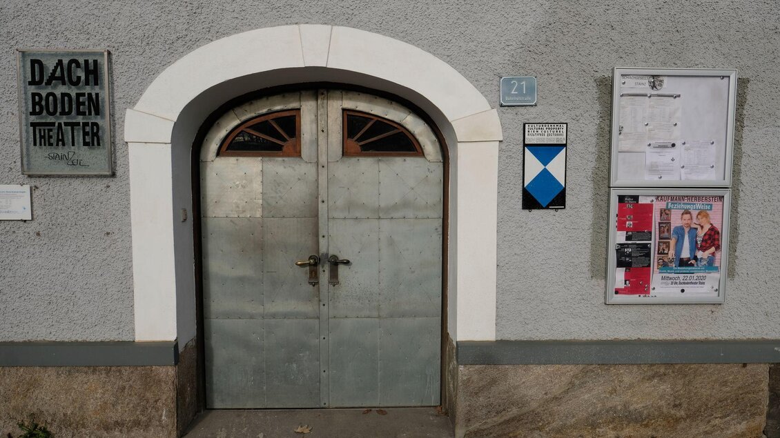 Ein alteingesessenes Theater mit einer metallischen Tür und einem Schild. Daneben befindet sich ein Veranstaltungshinweis an der Wand. | © Helmut Fladenhofer