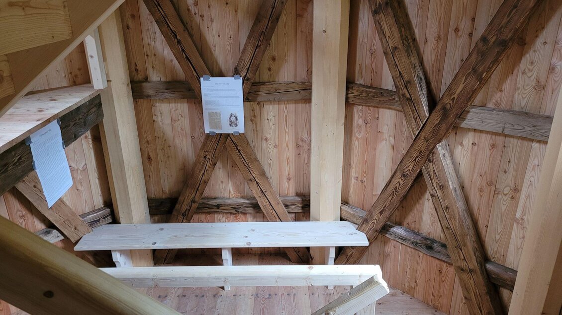 Eine Holztreppe mit einer offenen Struktur führt in einen Raum mit Holzwänden. An den Wänden hängen einige Informationen auf Papier. | © TV Südsteiermark - Irene Löschnig