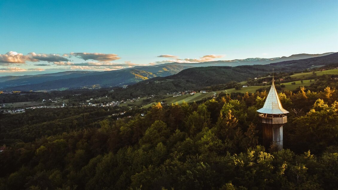 Ein Aussichtsturm inmitten einer grünen Landschaft. Im Hintergrund sind sanfte Hügel und ein klarer Himmel zu sehen. | © Zoran Novakovic - Schilcherland Steiermark
