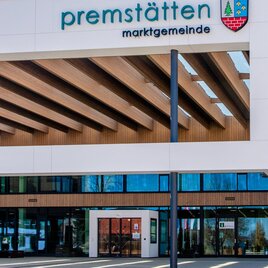 Ein modernes Gebäude mit Holzverkleidung und großen Fenstern. Darauf steht der Name „Premstätten Marktgemeinde“. | © Mias Photoart - Region Graz