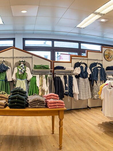 A well-known clothing store with traditional costumes and modern garments. The shelves are well-stocked and the floor is made of light wood. | © Landmarkt, Christian Wöhr