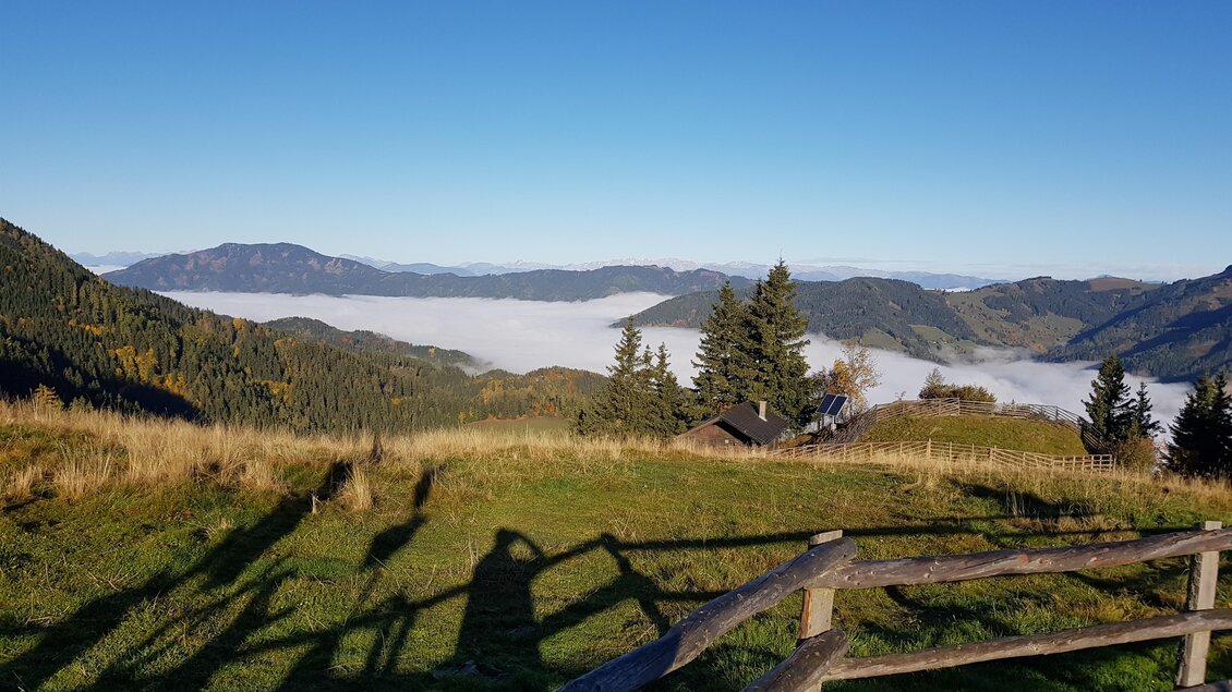 Eine malerische Berglandschaft mit sanften Hügeln und dichten Wäldern. Im Hintergrund liegt eine Nebelbank, die die Täler umhüllt. | © Stohandhütte