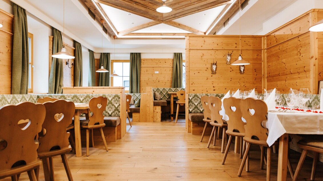 Ein gemütliches Restaurant mit Holzmöbeln und herzförmigen Stühlen. Große Fenster lassen viel Licht herein und schaffen eine einladende Atmosphäre. | © Hotel Restaurant Stockinger