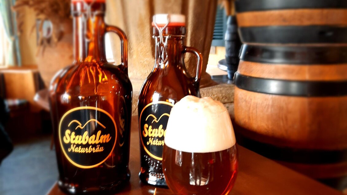 Zwei Flaschen und ein Glas Bier der Stubalmbrauerei Köflach auf Holztisch in rustikalem Ambiente. | © Stubalmbräu-Mara