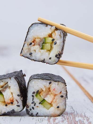 Maki die mit Gurke und Lachs gefüllt sind werden von Stäbchen gehalten mit hellem Hintergrund. | © Pixabay