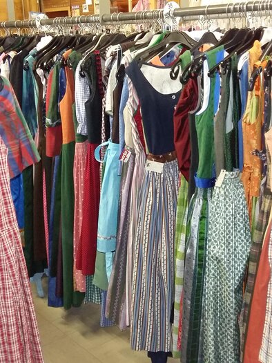 A clothing rack with a variety of colorful dresses. In the foreground, a checkered dress can be seen, while additional models hang in the background. | © Kirchschlager Petra