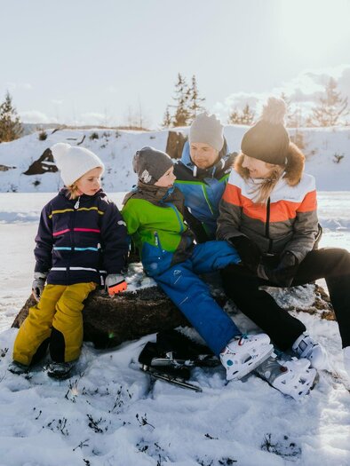 Eine Gruppe von Kindern sitzt im Schnee und genießt die Winterzeit. Sie tragen bunte Winterkleidung und wirken fröhlich. | © TV Südsteiermark - Lupi Spuma