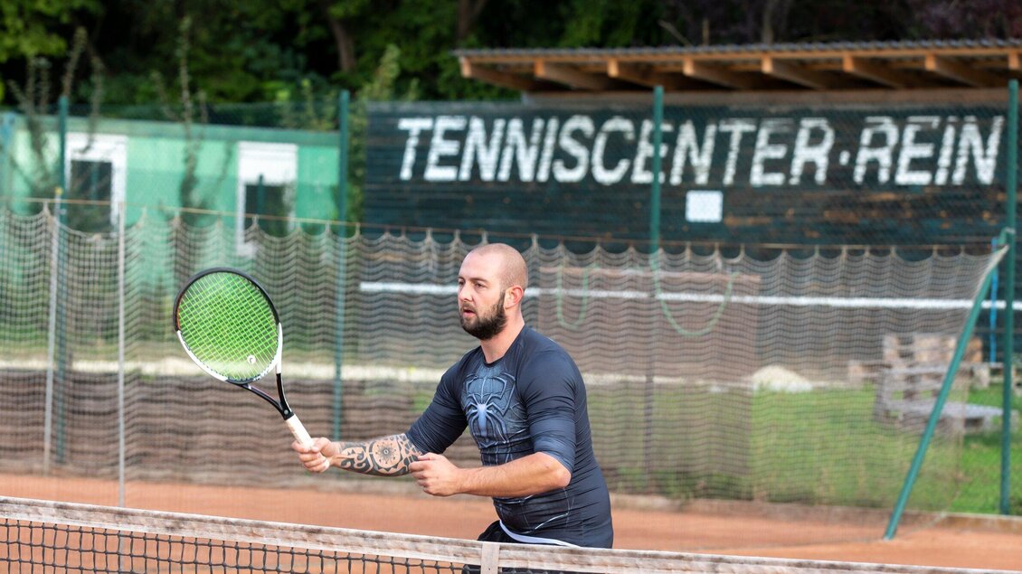 Ein Mann spielt Tennis auf einem Außenplatz. Im Hintergrund ist das Tenniscenter sichtbar. | © TV Region Graz - Lunghammer