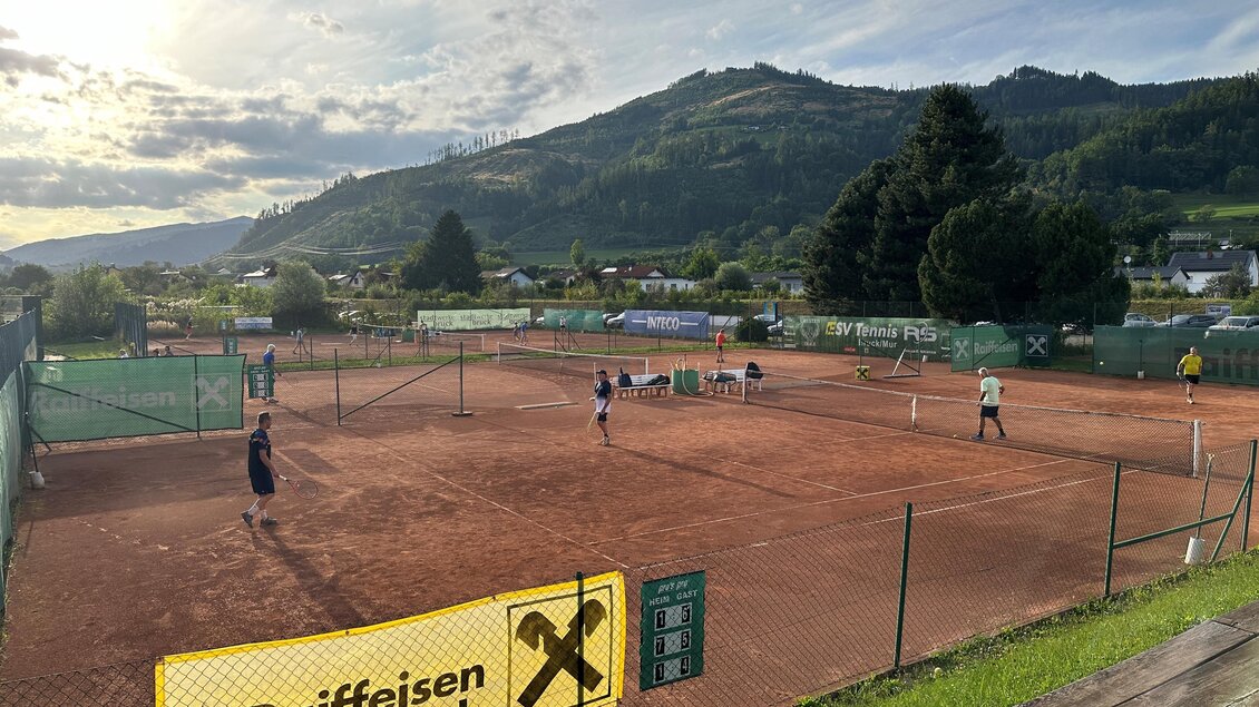 Auf einem Tennisplatz sind Spieler aktiv. Im Hintergrund sind Berge und ein klarer Himmel zu sehen. | © Anna-Lena König