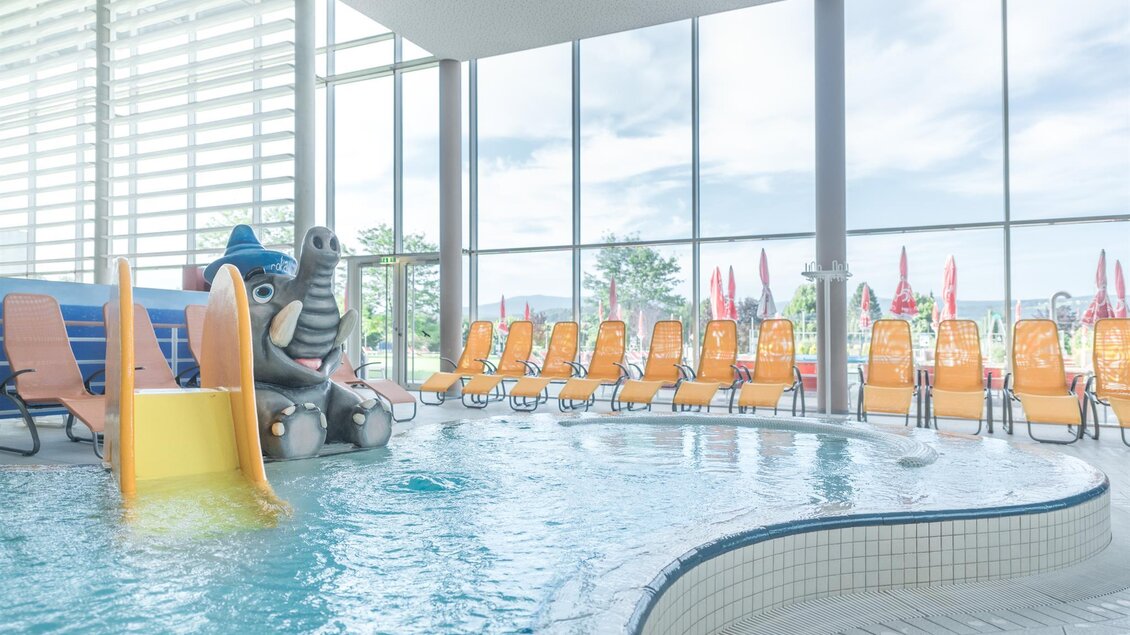 Kinderbereich der Therme NOVA in Köflach mit flachem Pool, Spielgerät und Liegen vor großen Fenstern im Innenbereich. | © Hotel & Therme NOVA
