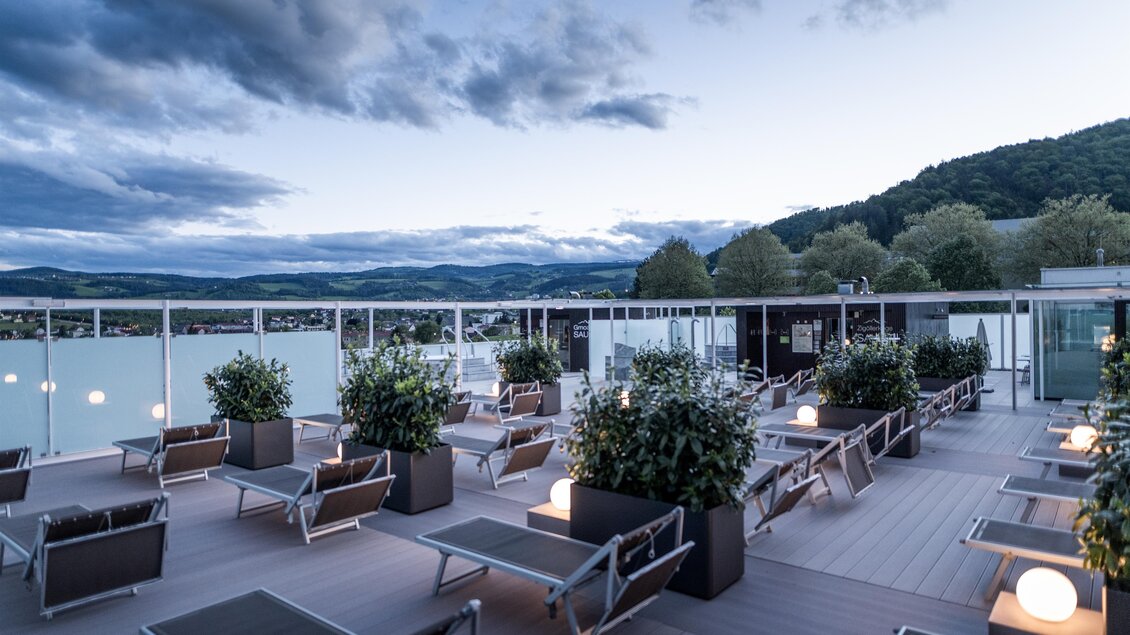 Dachterrasse der Therme NOVA in Köflach mit Liegen, Sitzbereichen und Blick auf die steirische Hügellandschaft bei Abendlicht. | © TV Region Graz - Die Abbilderei