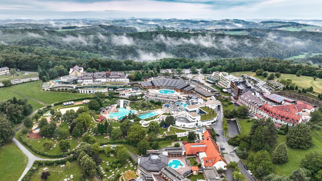 <p>Ein weitläufiges Resort mit mehreren Gebäuden und verschiedenen Schwimmbädern. Umgeben von grünen Wäldern und sanften Hügeln. Thermenresort Loipersdorf in Bad Loipersdorf.</p> | © TRL