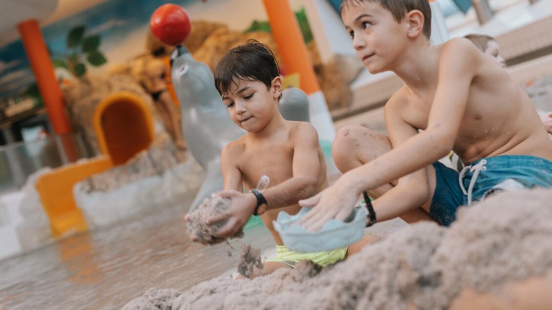<p>Zwei Jungen spielen im Sand in einem Wasserpark. Sie wirken glücklich und genießen ihre Zeit miteinander. Thermenresort Loipersdorf in Bad Loipersdorf.</p> | © TRL