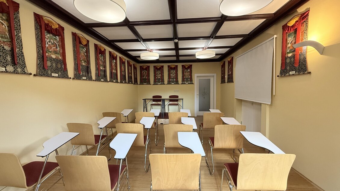 Ein leerer Klassenraum mit Tischen und Stühlen. An den Wänden hängen dekorative Bilder und es gibt ausreichende Beleuchtung. | © Tibetzentrum Institut