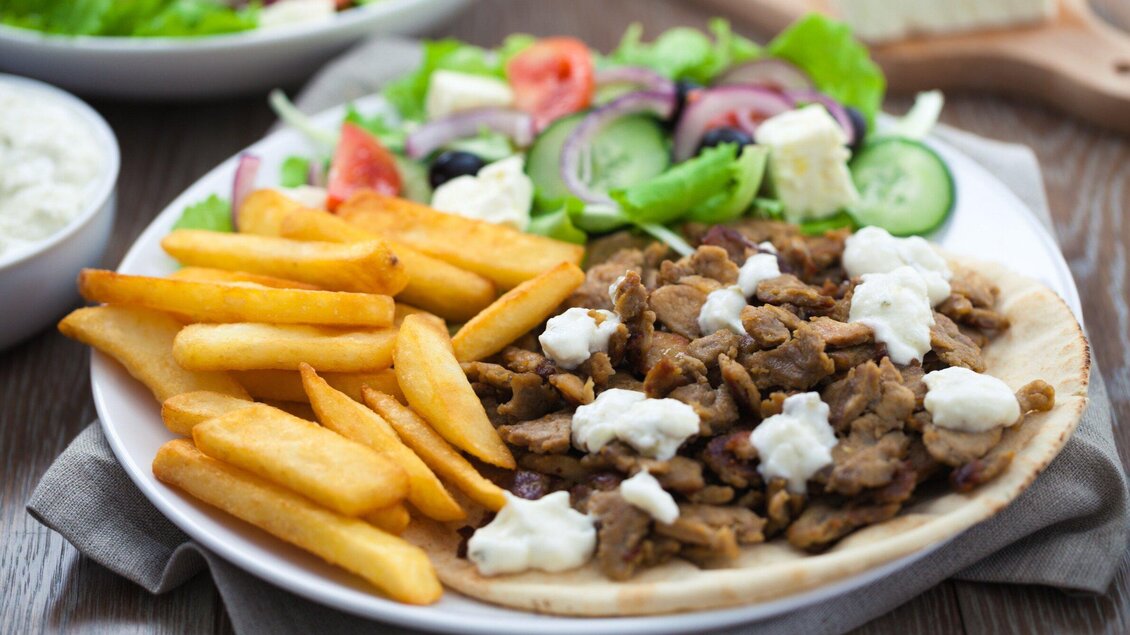 Ein Teller mit saftigem Fleisch, Pommes frites und einem frischen Salat. Dazu gibt es eine cremige Sauce. | © Tinos