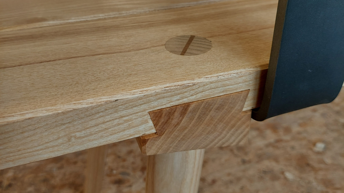 Ein detailreicher Blick auf einen Holzstuhl mit einem traditionellen Verbindungselement. Die Oberfläche ist glatt und zeigt die natürliche Maserung des Holzes. | © Tischlerei Egger