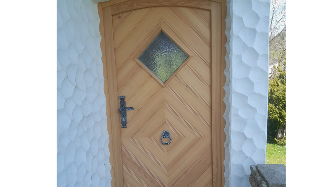 Eine schöne Holz-Entratntür mit einem diamantförmigen Fenster. Die Tür ist in einem natürlichen Stil gestaltet und befindet sich in einer hellen Umgebung. | © Tischlerei Egger
