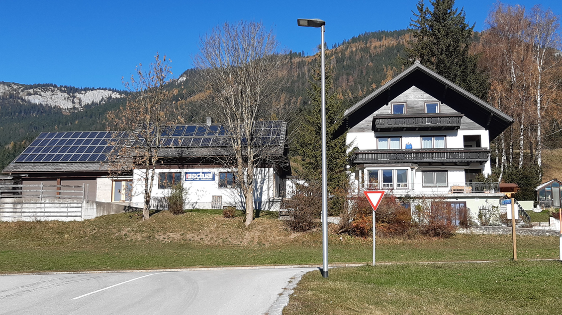 Zwei Häuser in den Bergen, das linke mit Solarpanelen und das rechte im traditionellen Stil. Im Hintergrund eine klare, blaue Himmel und grüne Wiesen. | © TVB Ausseerland Salzkammergut_Daniela Casari
