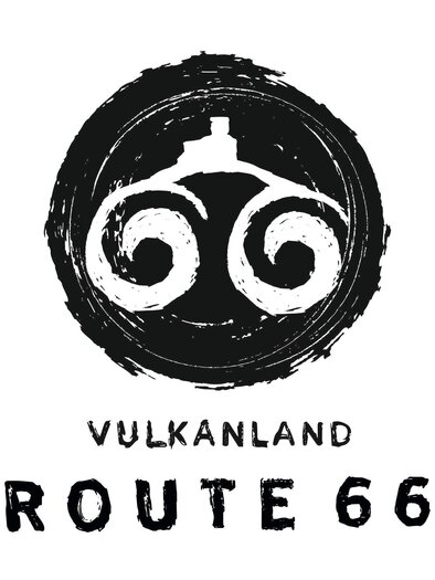 Ein Logo mit dem Schriftzug "Vulkanland" und "Route 66". Darunter sind künstlerisch gestaltete, spiralförmige Elemente zu sehen.