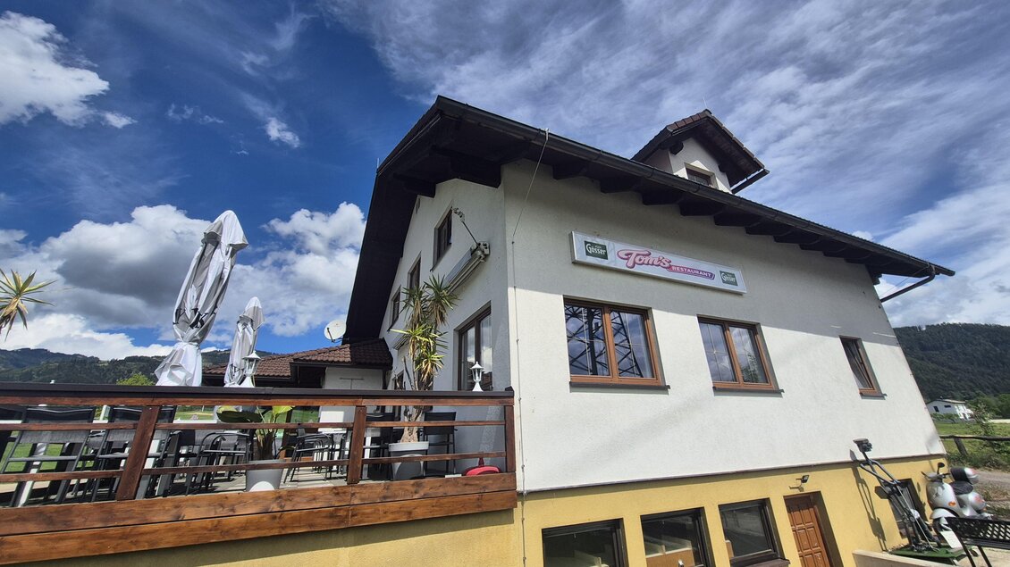 Ein modernes Gebäude mit einem charmanten Balkon und schöner Holzverkleidung. Der Himmel ist blau und es gibt vereinzelte Wolken. | © Andrea Stelzer