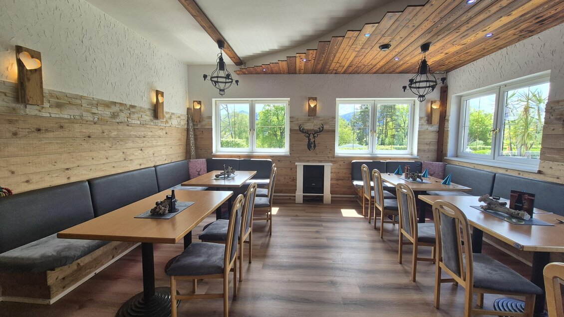 Ein gemütliches Restaurant mit Holzwänden und Tischen aus Holz. Große Fenster lassen viel Licht herein und bieten einen Blick ins Grüne. | © Andrea Stelzer
