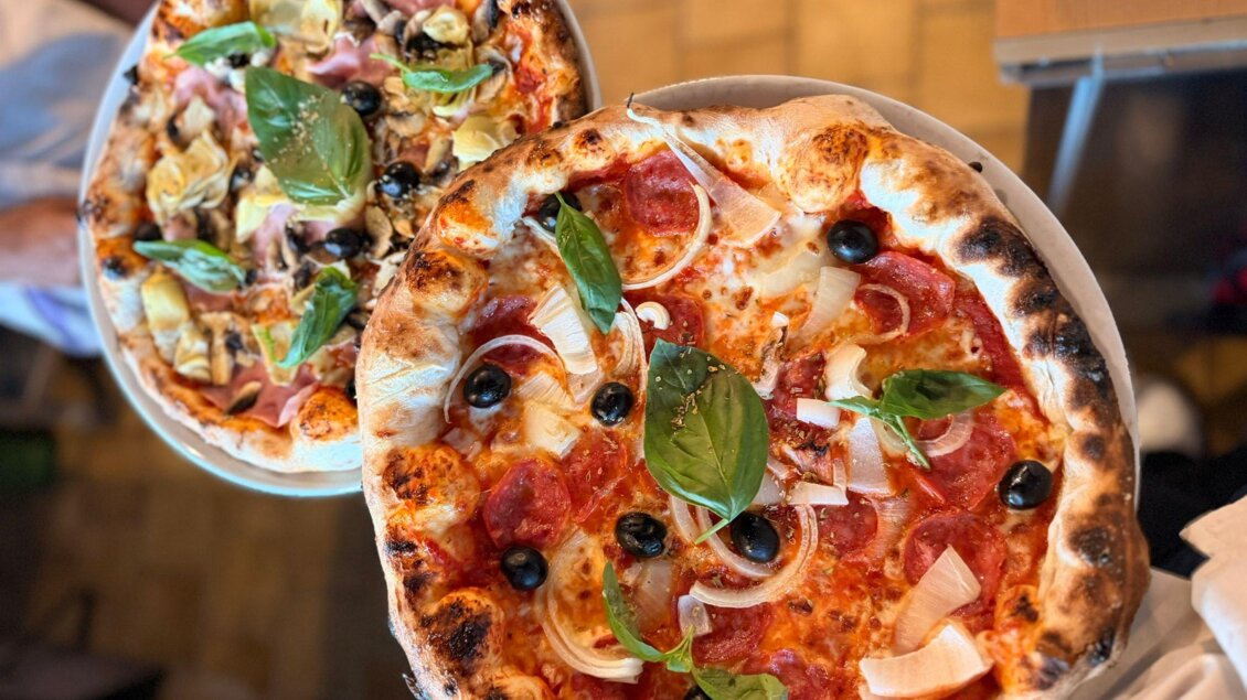 Zwei große Pizzen auf einem Teller, eine mit Salami und Basilikum, die andere mit Gemüse. Beide Pizzen haben einen krossen Rand und sind appetitlich angerichtet. | © Trattoria la Fortuna