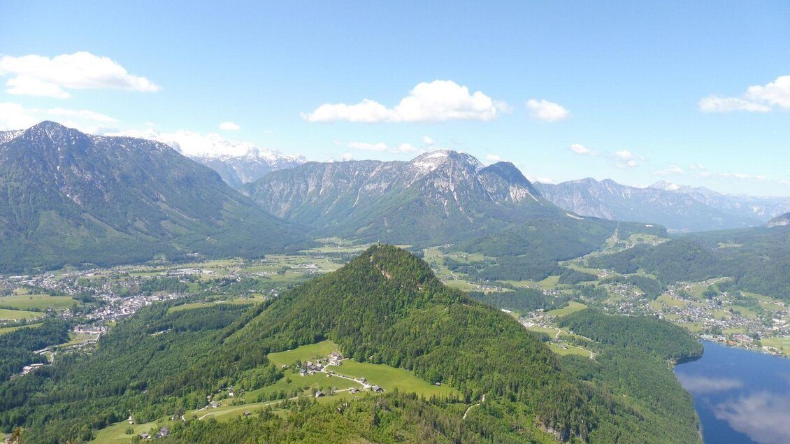 Mittig ist der Tressenstein zwischen Altaussee mit dem Altausseersee (rechts vom Bild), Bad Aussee, und Grundlsee zu sehen. Ganz oben erhebt sich die hölzerne Aussichtsplattform Tressensteinwarte zwischen den tiefgrünen Bäumen des Tressensteins, umgeben von dem Bergpanorama des Ausseerlandes. | © TVB Ausseerland - Salzkammergut/Wolfgang Kreutzer